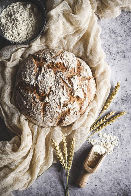 Домашний хлеб с шипами на ткани, мука с деревянной лопаткой — стоковое фото