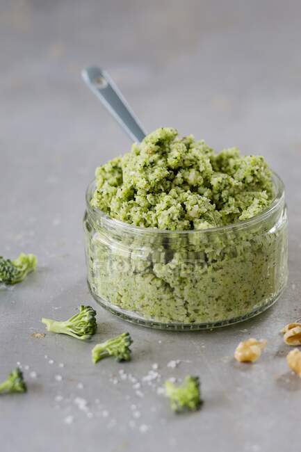Broccoli and walnut pesto in a glass ramekin with a ceramic spoon — Stock Photo