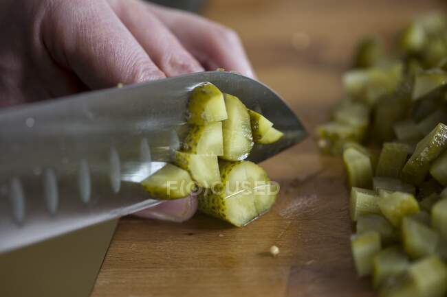 Cortar pepinillos con un cuchillo Santoku - foto de stock