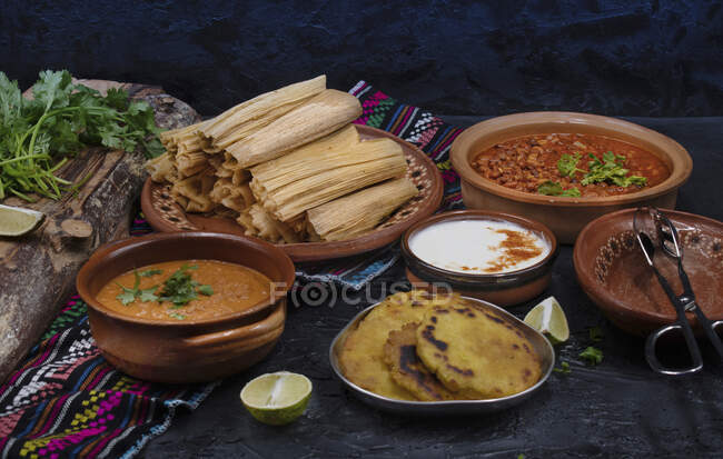 Tamales végétaliens remplis de seitan, masa, chili verde et servis avec sauce ranchero, crème et haricots chili — Photo de stock