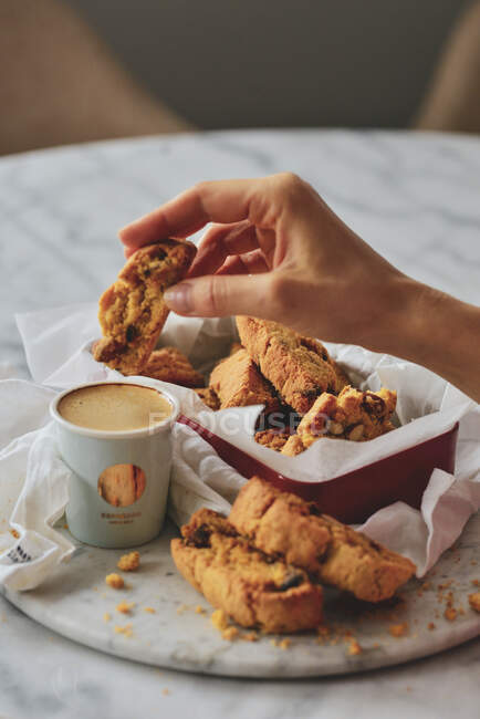 Mão com um biscoito e uma xícara de café — Fotografia de Stock
