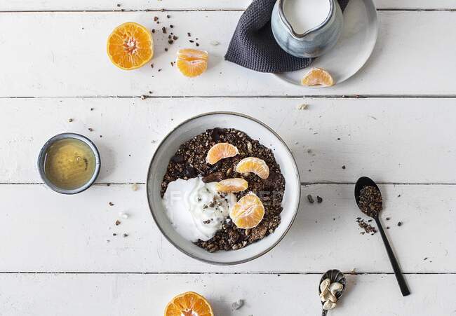 Chocolate muesli with yoghurt and tangerines in bowl — Stock Photo