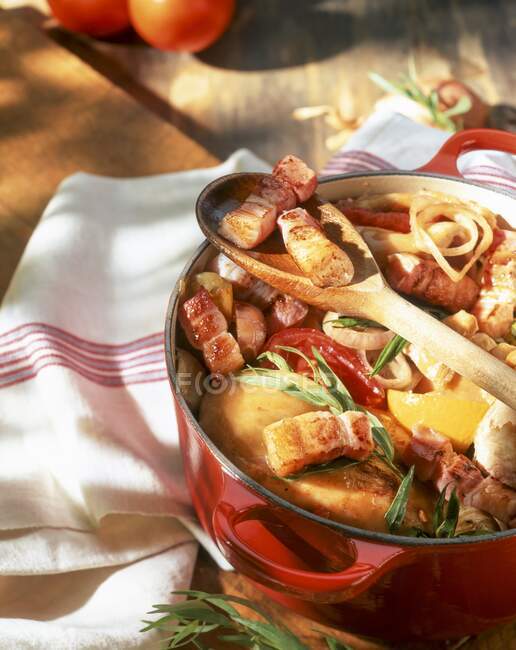 Chicken with bacon strips, tomatoes and tarragon in a casserole dish — Stock Photo