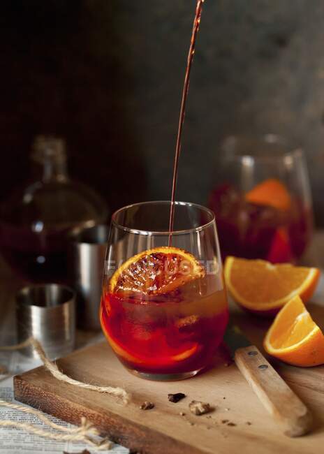 Um cocktail Negroni a ser derramado num copo — Fotografia de Stock
