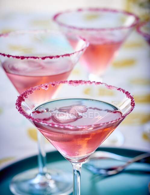 Cosmopolitan cocktails with pink sugar and ice cubes in glasses — Stock Photo