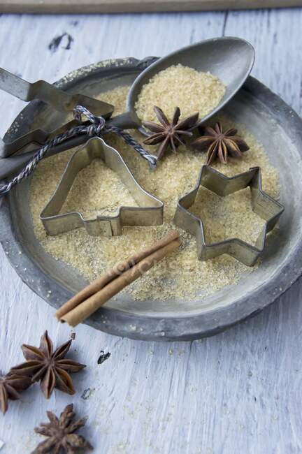 A plate with cookie cutters, a spoon, sugar, star anise and a cinnamon stick — Stock Photo