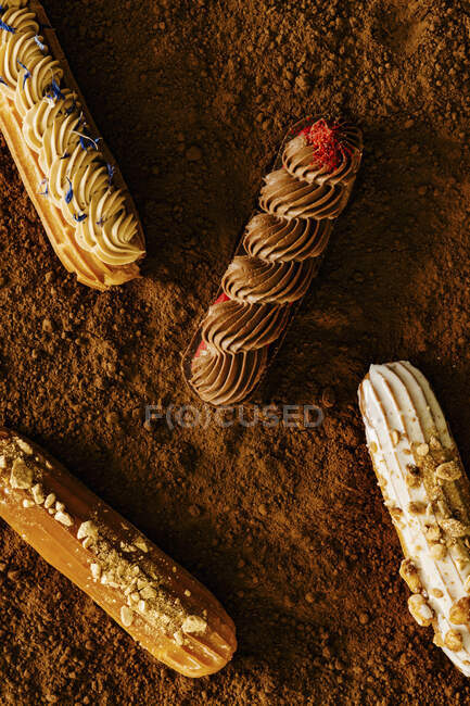 Ремесленные французские эклеры на текстуре какао-порошка — стоковое фото