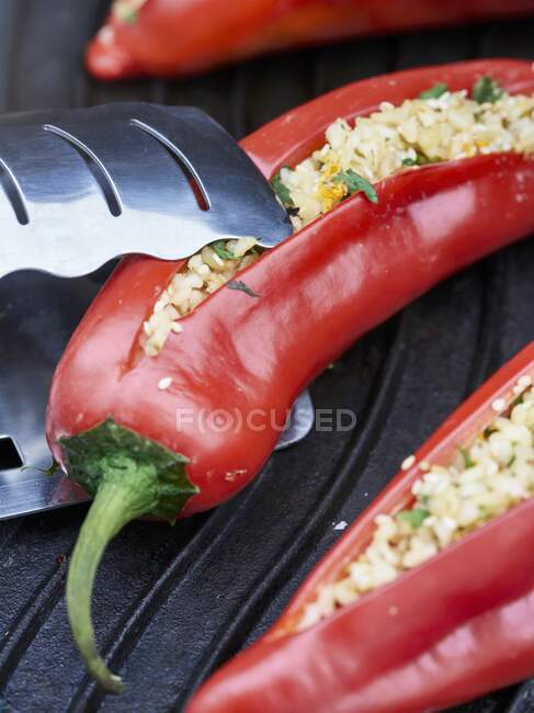 Peperoni rossi ripieni di grano bulgur ed erbe su una griglia — Foto stock