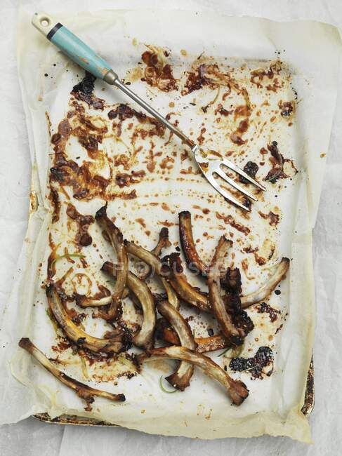 The bone leftovers of sticky ribs on paper — Stock Photo