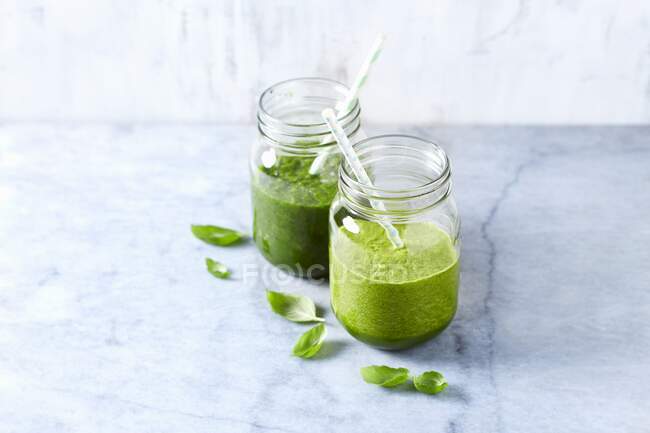 An apple and spinach smoothie and an apple and kale smoothie with basil — Stock Photo