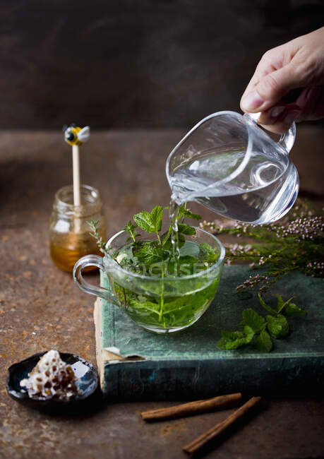 Té con hojas verdes y menta fresca sobre un fondo de madera - foto de stock