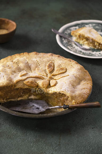 Apple pie in tin with spatula and portion on background — Stock Photo
