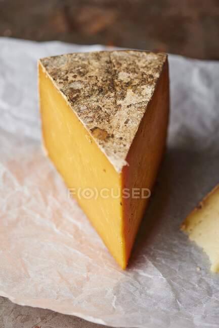 Шматок нарізаного сиру на паперовій обгортці — стокове фото