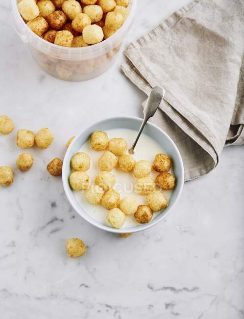 Corn pops in a plastic tub and in a bowl with milk — Stock Photo