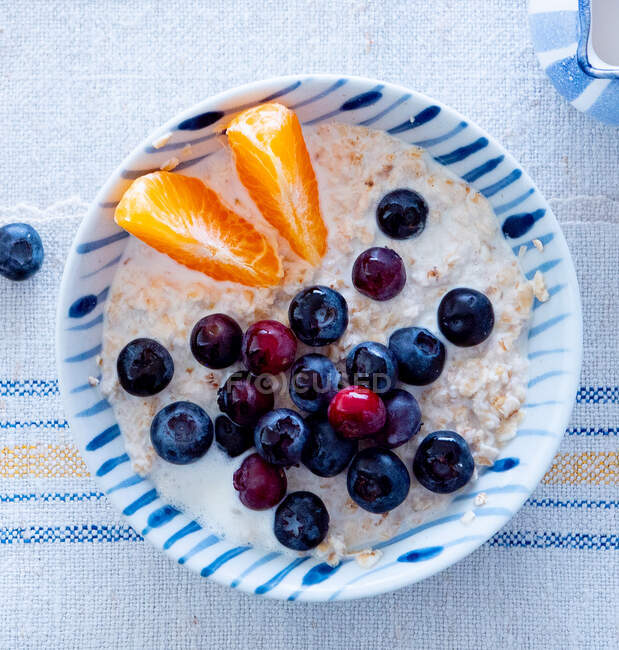 Porridge with blueberries and mandarins in ceramic bowl — Stock Photo