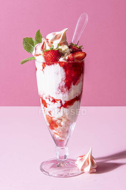 Sundae aux fraises avec crème glacée, crème fouettée, meringue concassée, sauce aux fraises et menthe — Photo de stock