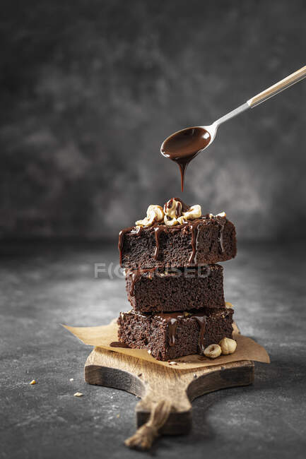 Stack of brownie with nuts and pouring chocolate sauce — Stock Photo