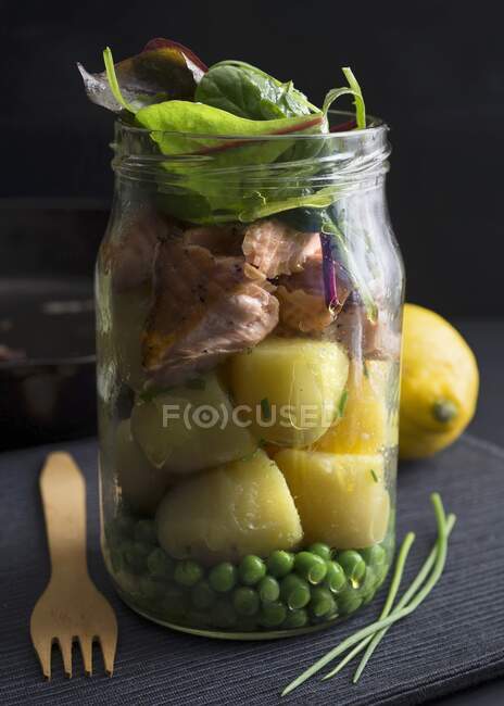 Steamed salmon and potatoes in a glass jar with peas and chard — Stock Photo