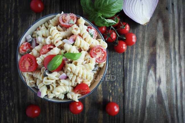 Pasta salad with basil, tomatoes, black olives, red onion and feta cheese — Stock Photo