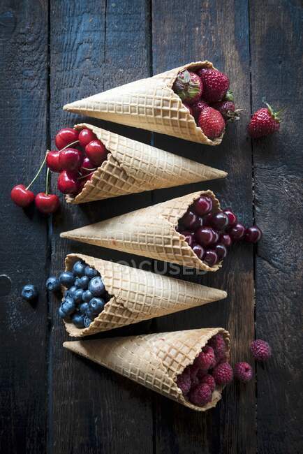 Diverses baies et cerises dans des cônes de crème glacée — Photo de stock