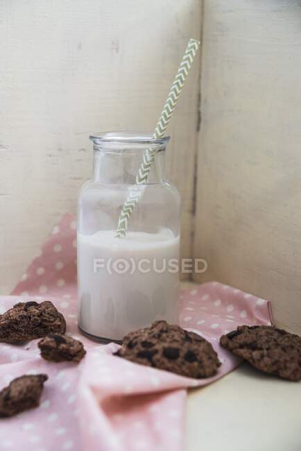 Una bebida a base de plantas en una botella de vidrio con galletas de chocolate vegano al lado - foto de stock