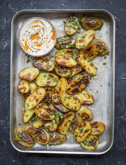 Roasted potatoes on baking tray with parsley and garlic — Stock Photo