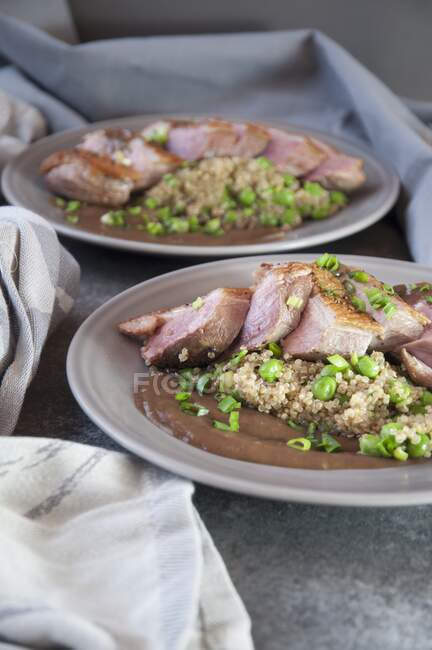 Duck breast with quinoa, a brown sauce and peas — Stock Photo