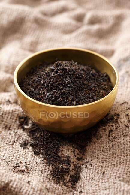 Tè nero in una ciotola di metallo su un panno di iuta — Foto stock