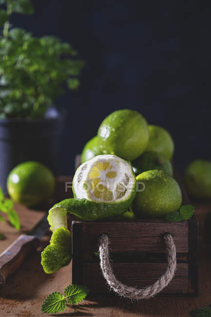 Fresh wet limes in a wooden box — Stock Photo