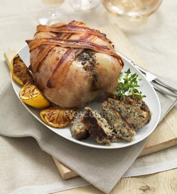 A roast chicken with strips of bacon — Stock Photo