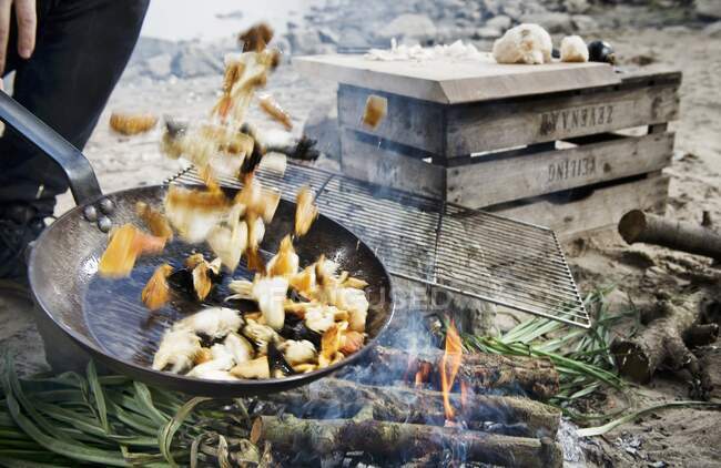 Camping food in a pan tossed over a camp fire — Stock Photo