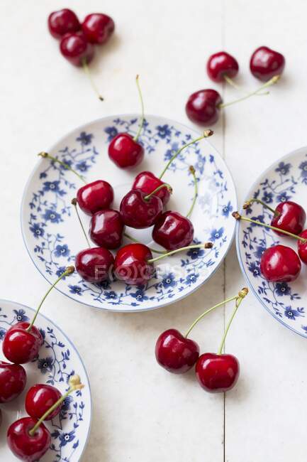 Cerejas frescas em pratos e ao lado — Fotografia de Stock