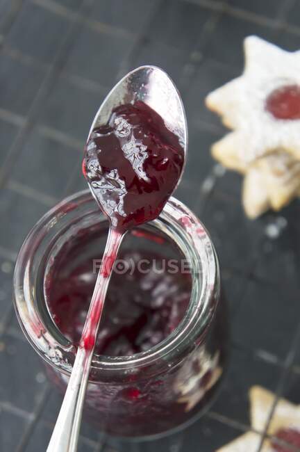 Johannisbeermarmelade im Glas mit einem Löffel zum Füllen von Marmeladenkeksen — Stockfoto