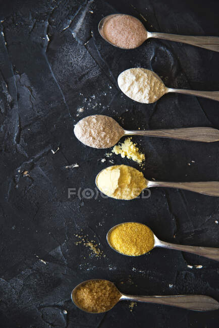 Colheres de chá com tipos de farinha de milho farinha de trigo sarraceno açúcar e sal — Fotografia de Stock
