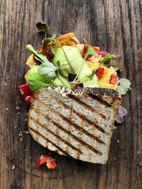 Gegrilltes Sandwich mit Avocado und Ei auf Holzoberfläche — Stockfoto