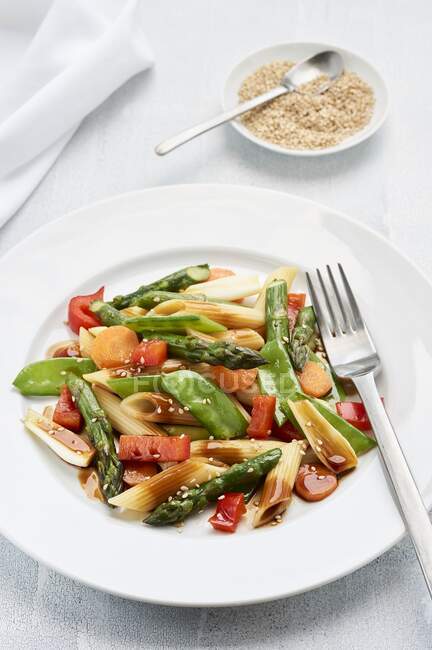 Asian style pasta salad with green asparagus, sugar snap peas, spring onions, red peppers, and carrots — Stock Photo