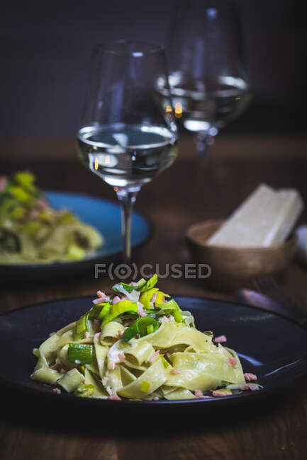 Tagliatelle with salmon and leek, glasses of drink on background — Stock Photo