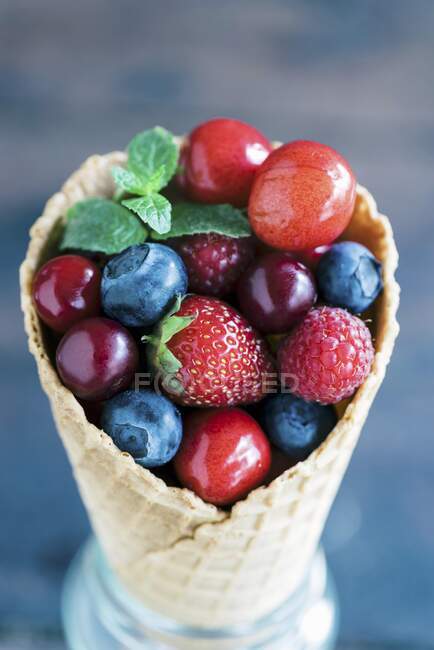 Bagas frescas e cerejas em um cone de sorvete — Fotografia de Stock