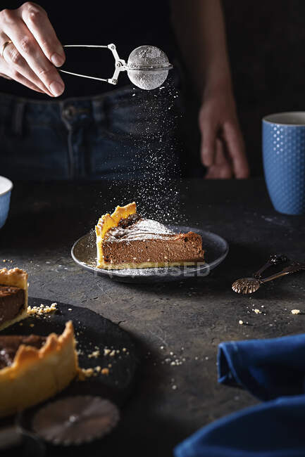 Chocolate cream cake being dusted with icing sugar — Stock Photo
