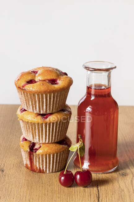 Freshly baked cherry muffins and bottle of stewed fruits drink — Stock Photo