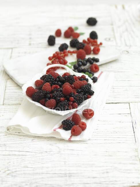 Fresh summer berries in and next to a bowl — Stock Photo