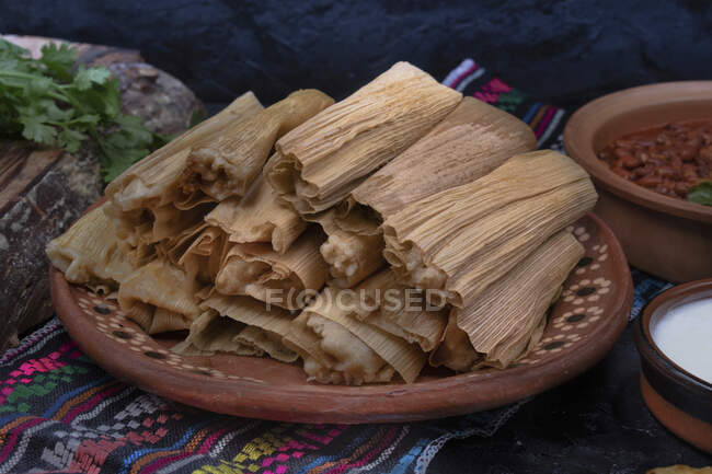 Vegan tamales filled with seitan, masa, chile verde and served with ranchero sauce, cream and chili beans — Stock Photo