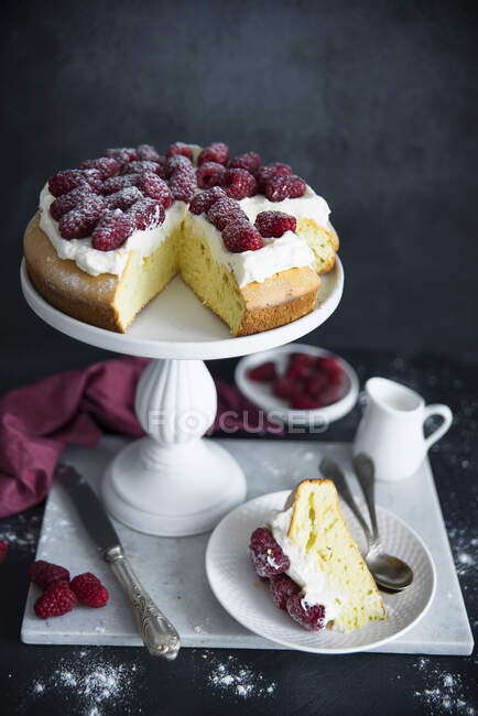 Sponge cake with whipped cream, raspberries and powdered sugar — Stock Photo