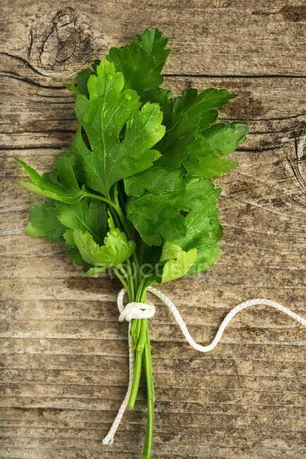 A bunch of smooth parsley on a wooden background (top view) — Stock Photo