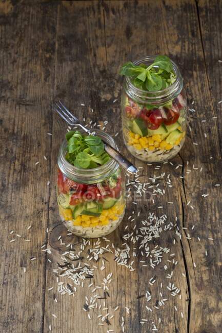 Rice salad in a glass jar with wild rice, sweetcorn, cucumber, tomato and lamb's lettuce — Stock Photo