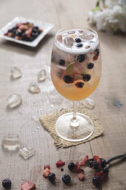 White Sangria with berries in a large wine glass and ice — Stock Photo