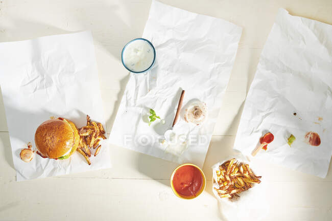 Hamburguesas comidas en la mesa con papeles a la izquierda - foto de stock