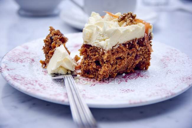 A piece of carrot cake with cream frosting on a plate — Stock Photo