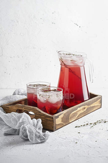 Punch de ciruela con hielo y tomillo en jarra y vasos - foto de stock