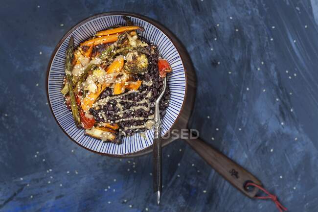 Eine vegane Buddha-Schüssel mit schwarzem Reis, geröstetem Gemüse und Tahini-Sauce — Stockfoto